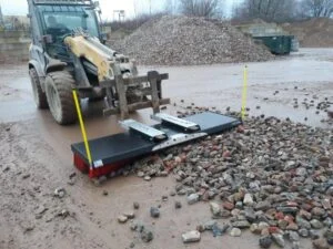 Tractor sweeper clearing mud and straw from a concrete farm yard