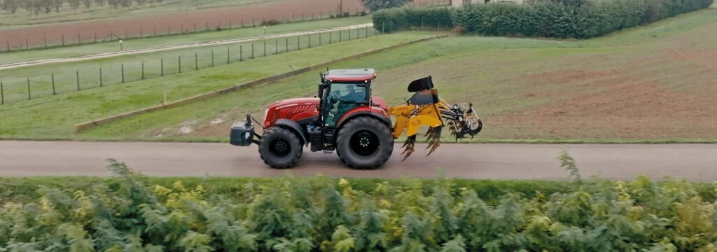 Tractor pulling a subsoiler through a stubble field to break up compacted soil